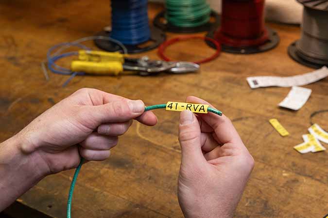 A person wrapping a wire with a label.
