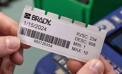 A person holding a newly printed barcode label with crisp legible printing right to the edge