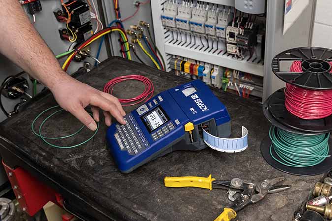A worker using an M510 label printer to identify wires.